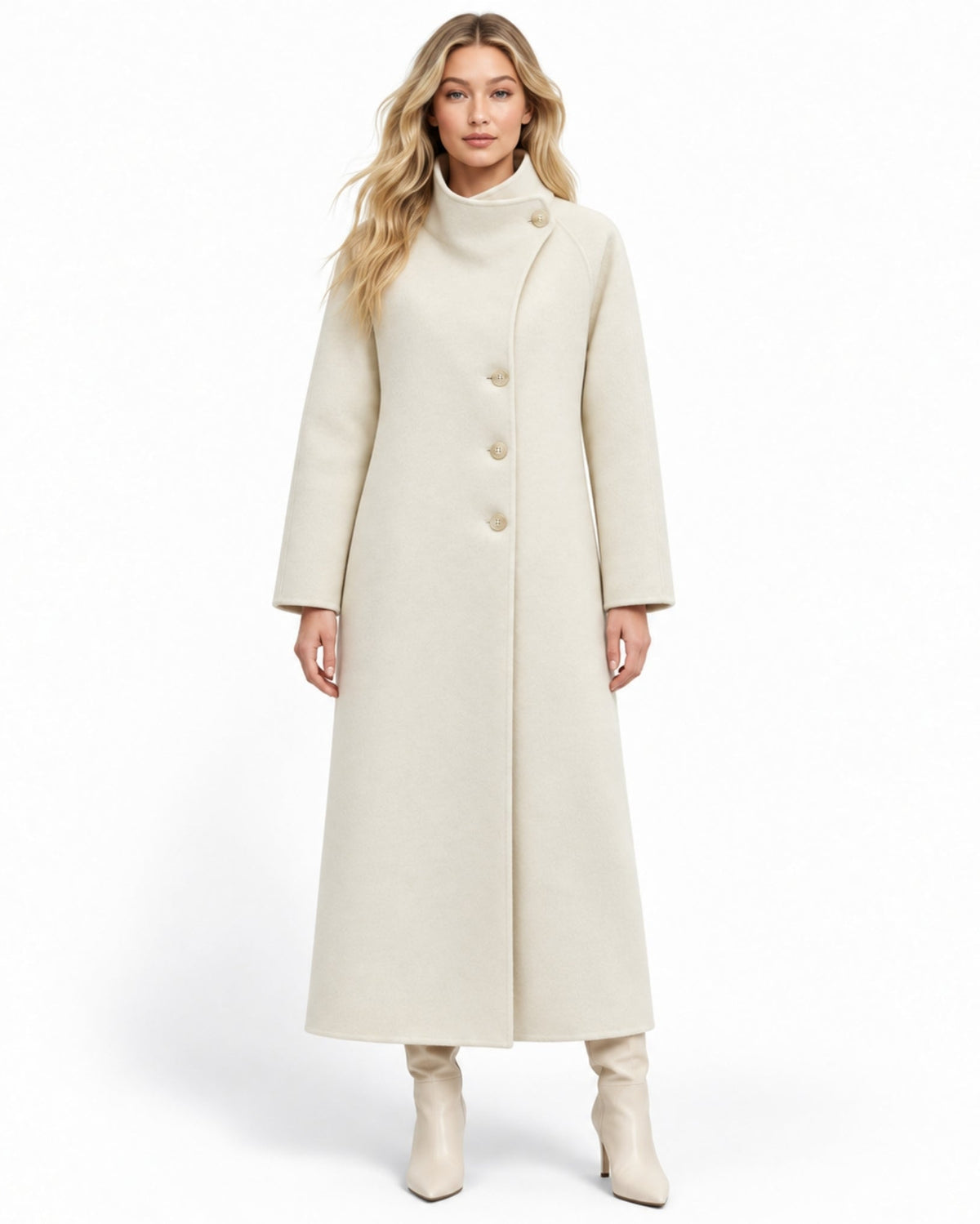 A woman modeling a long, mid-length cream-colored coat with a mock neck and asymmetrical button closure, paired with matching cream ankle boots, against a plain white studio background.