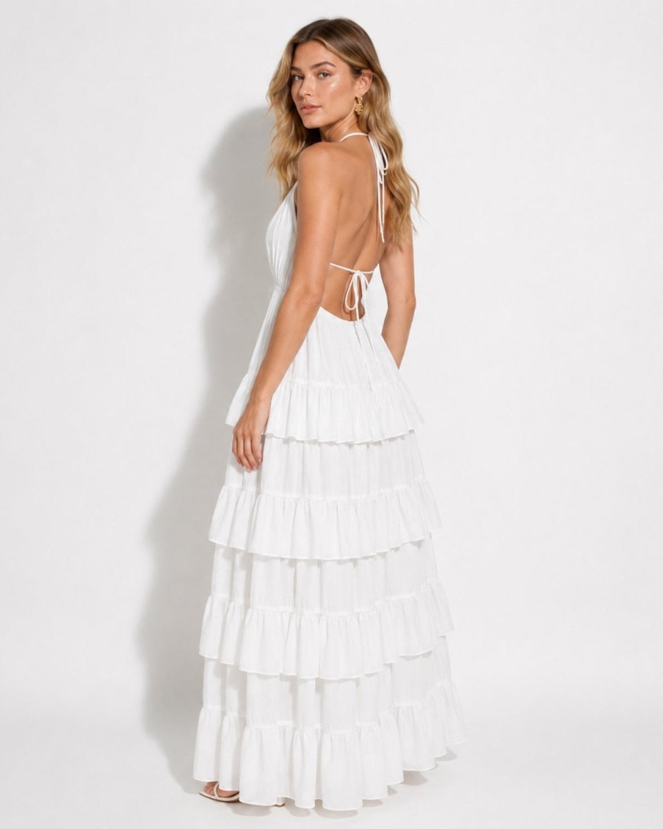 Studio product shot of a white luxury halter deep V-neck maxi dress, displaying the multi-tiered ruffle skirt design.