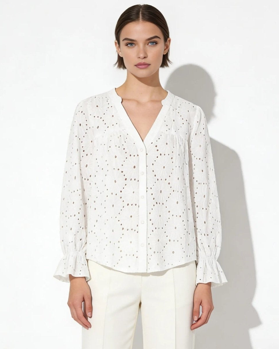 Model wearing the white lydia blouse with a v-neck and long sleeves, paired with cream trousers.