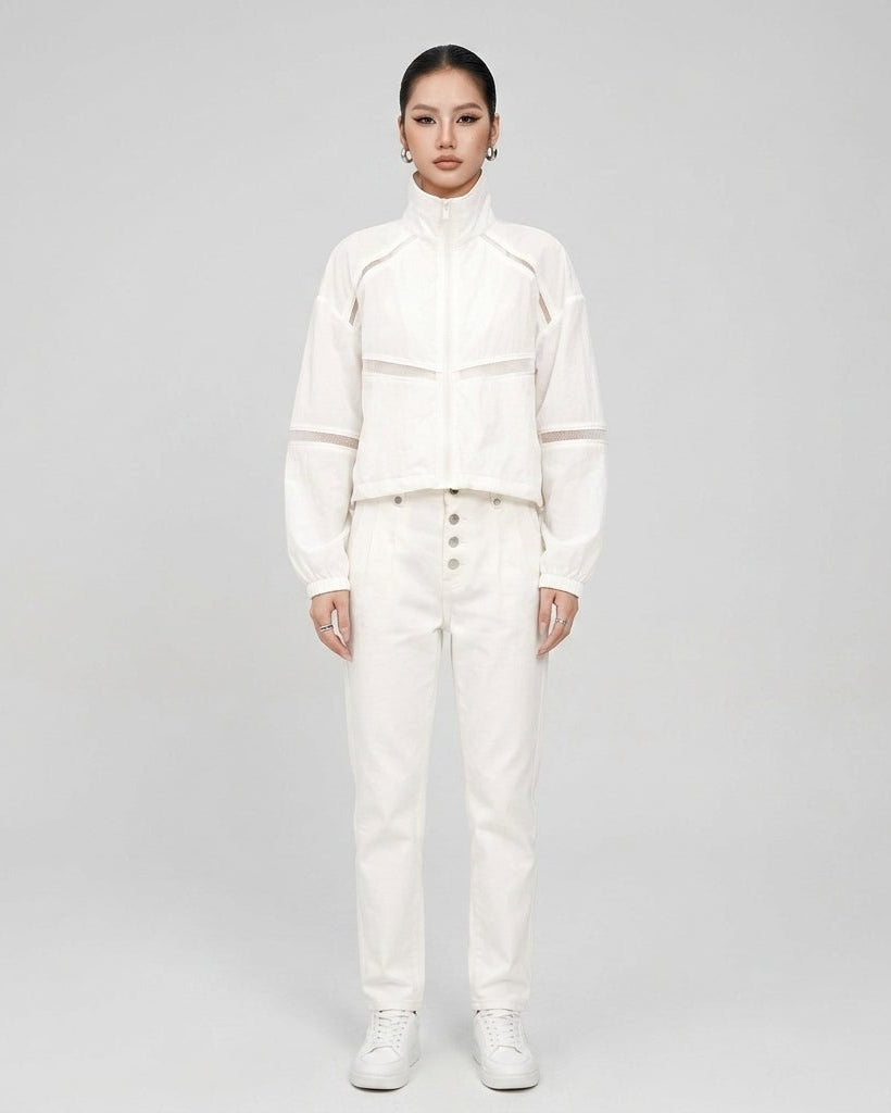 Full body studio shot of the white zip up athleisure jacket styled with matching high waisted denim