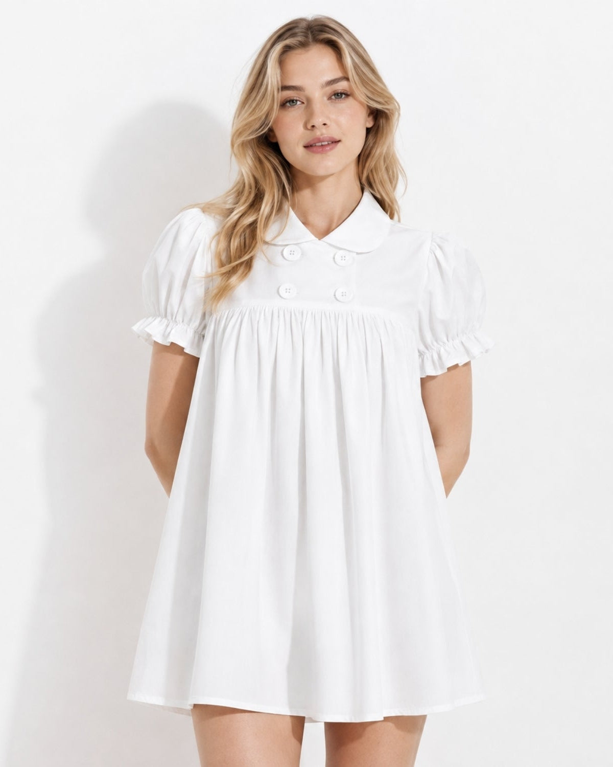 Front view of a woman modeling the pristine white luxury peter pan collar mini dress with elegant short puff sleeves