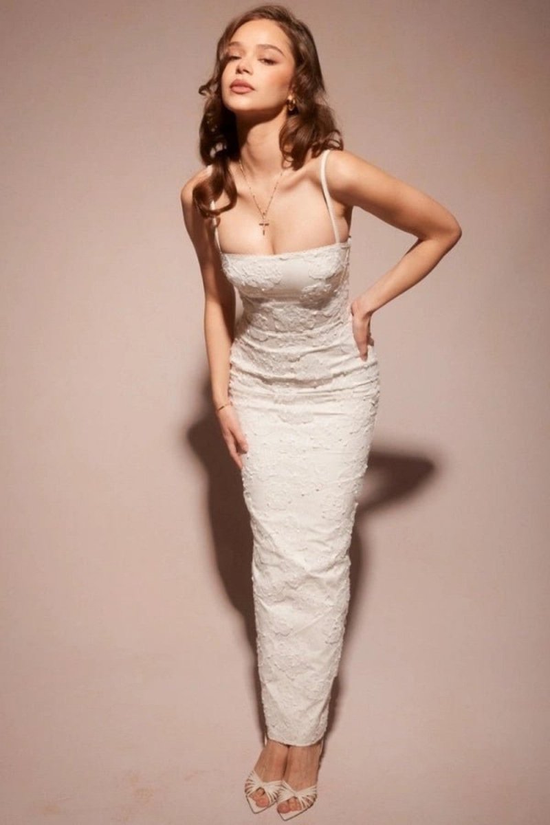 Woman wearing a white lace dress against a beige background