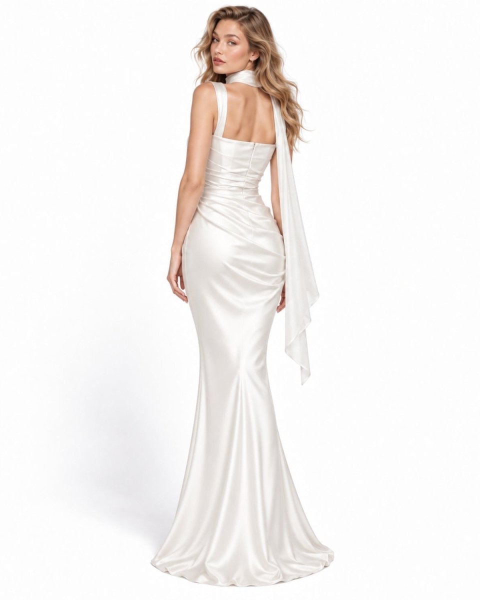 A woman modeling a floor-length white satin gown from the back, featuring a halter-style neckline with a draped fabric detail, ruched bodice, and a fitted mermaid silhouette on a clean white background.