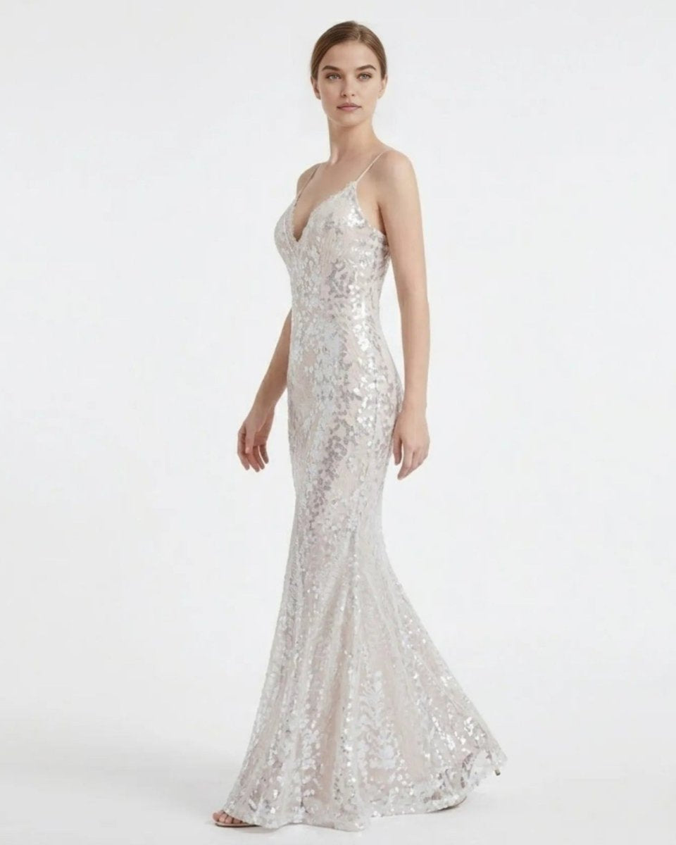 Side angle profile of a woman in a sparkling white sequin maxi prom dress, showcasing the form-fitting bodycon silhouette and thin spaghetti straps.