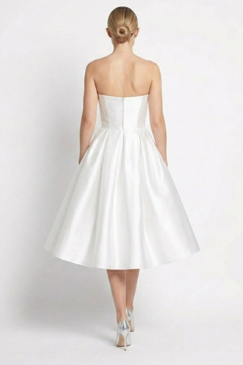 Back view of white strapless midi dress showing invisible zipper and pleated skirt details.