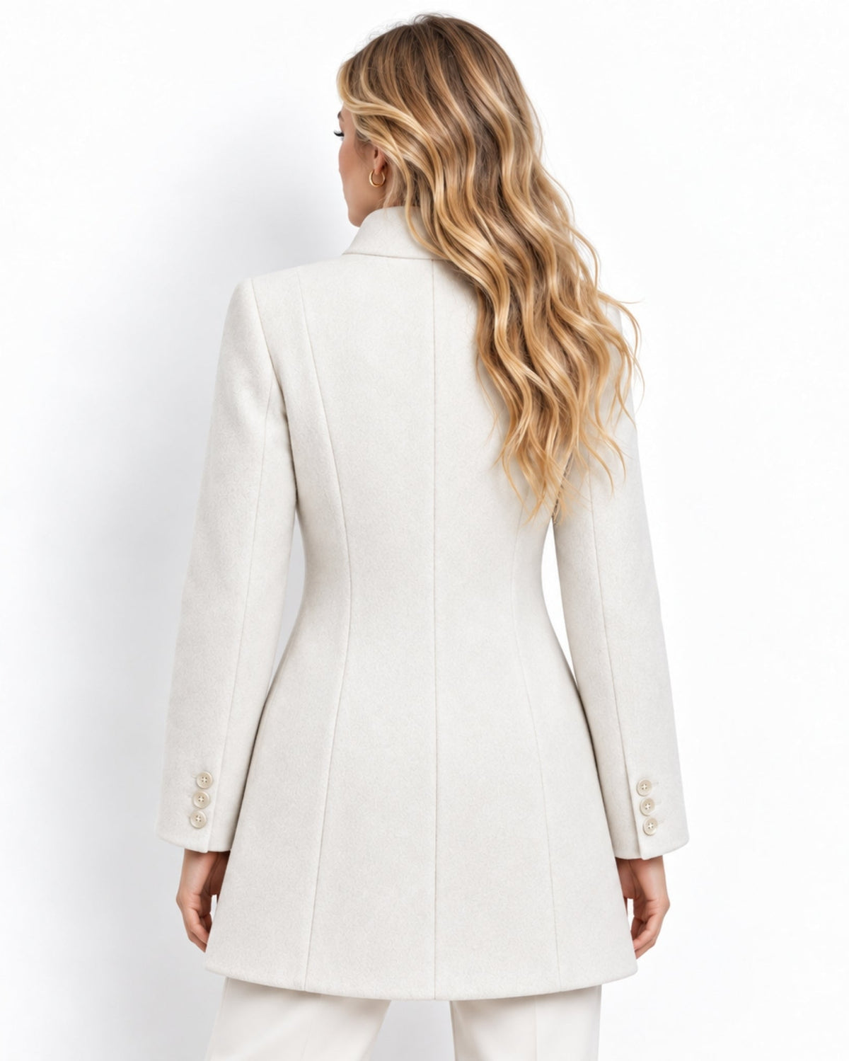 A woman viewed from the back wearing a structured cream-colored blazer with three decorative buttons on the cuffs, paired with matching trousers against a plain white background.