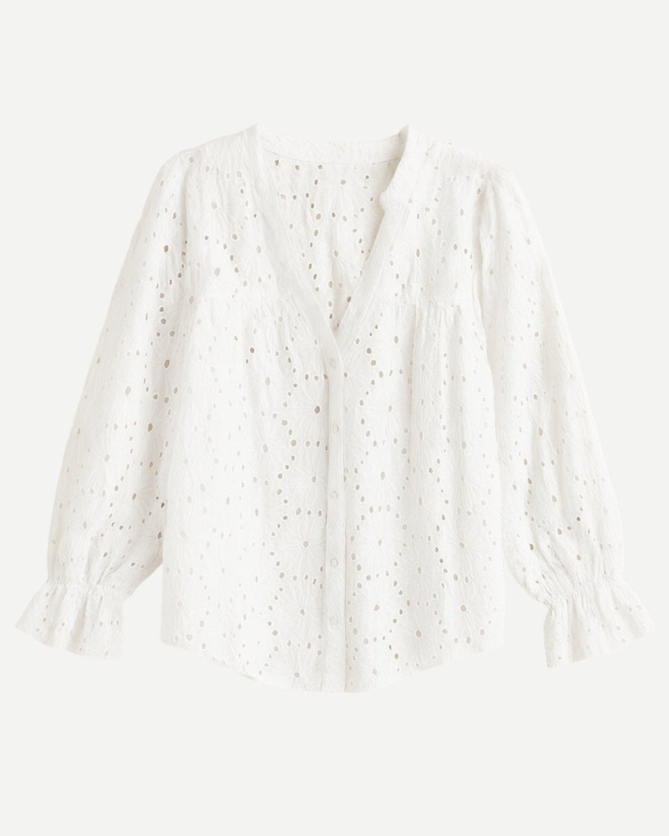 Flat lay of a white v-neck lydia blouse showing the button-front detail and long sleeves with ruffle cuffs.