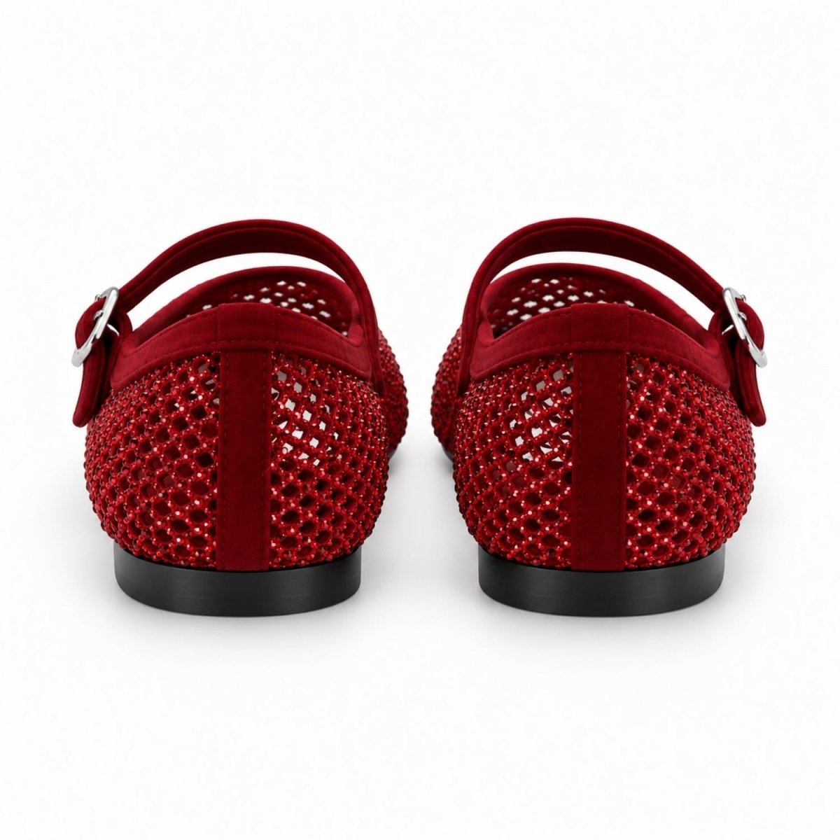 A pair of red flat shoes viewed from the back, featuring textured red mesh uppers with silver buckle straps and black soles, set against a plain white background.
