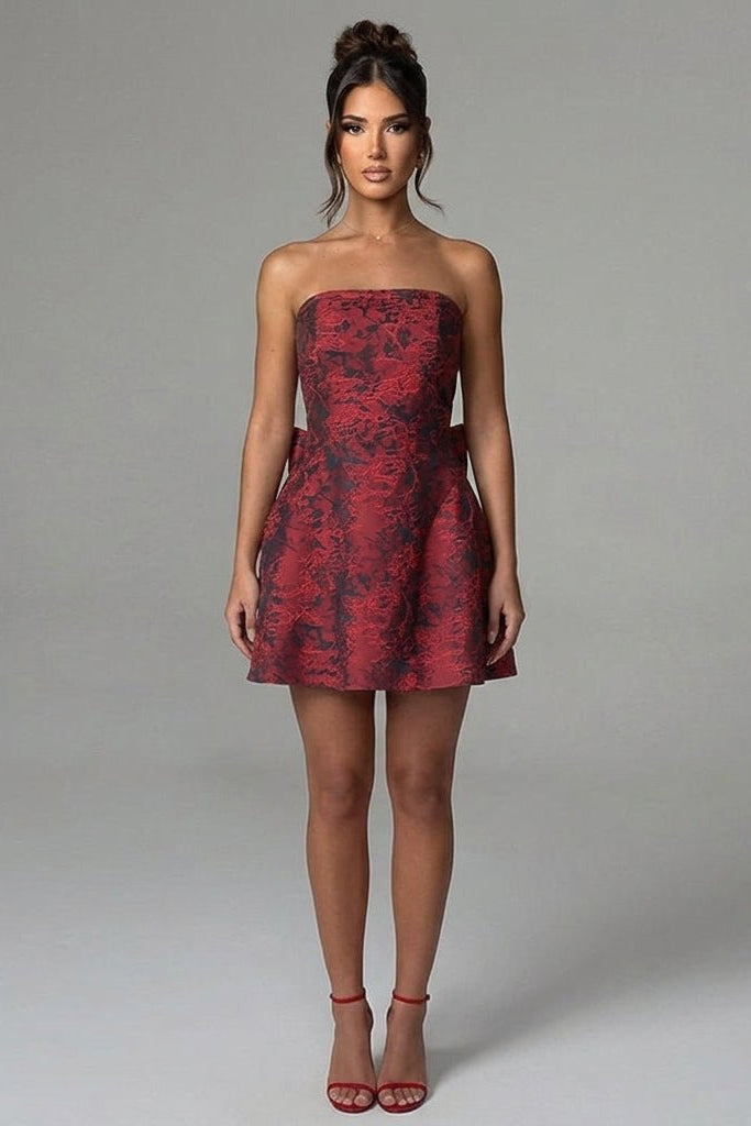 Woman modeling a wine red floral jacquard strapless mini dress featuring a structured A-line silhouette and elegant cocktail party styling.