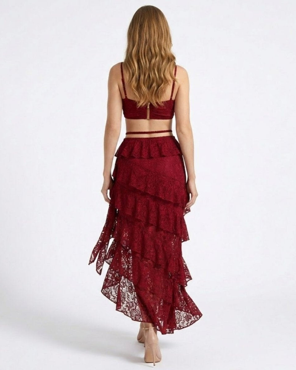 Back view of a wine red lace two piece skirt set showcasing an exposed gold back zipper on the crop top and cascading ruffles on the sheer lace train.
