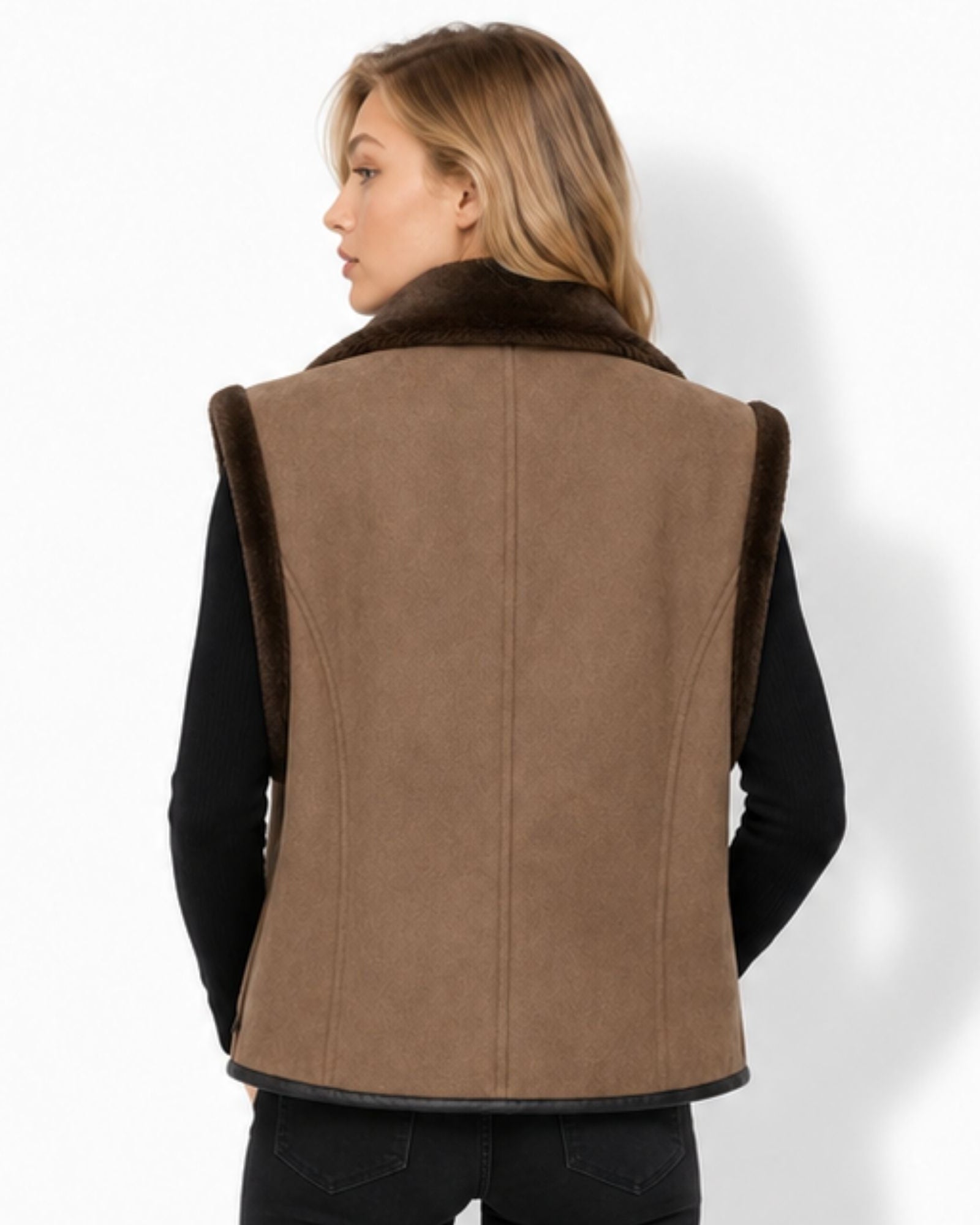 A woman shown from the back wearing a brown suede-like sleeveless vest with a dark brown faux-fur collar, over a black long-sleeve top and black pants, against a plain white studio background.