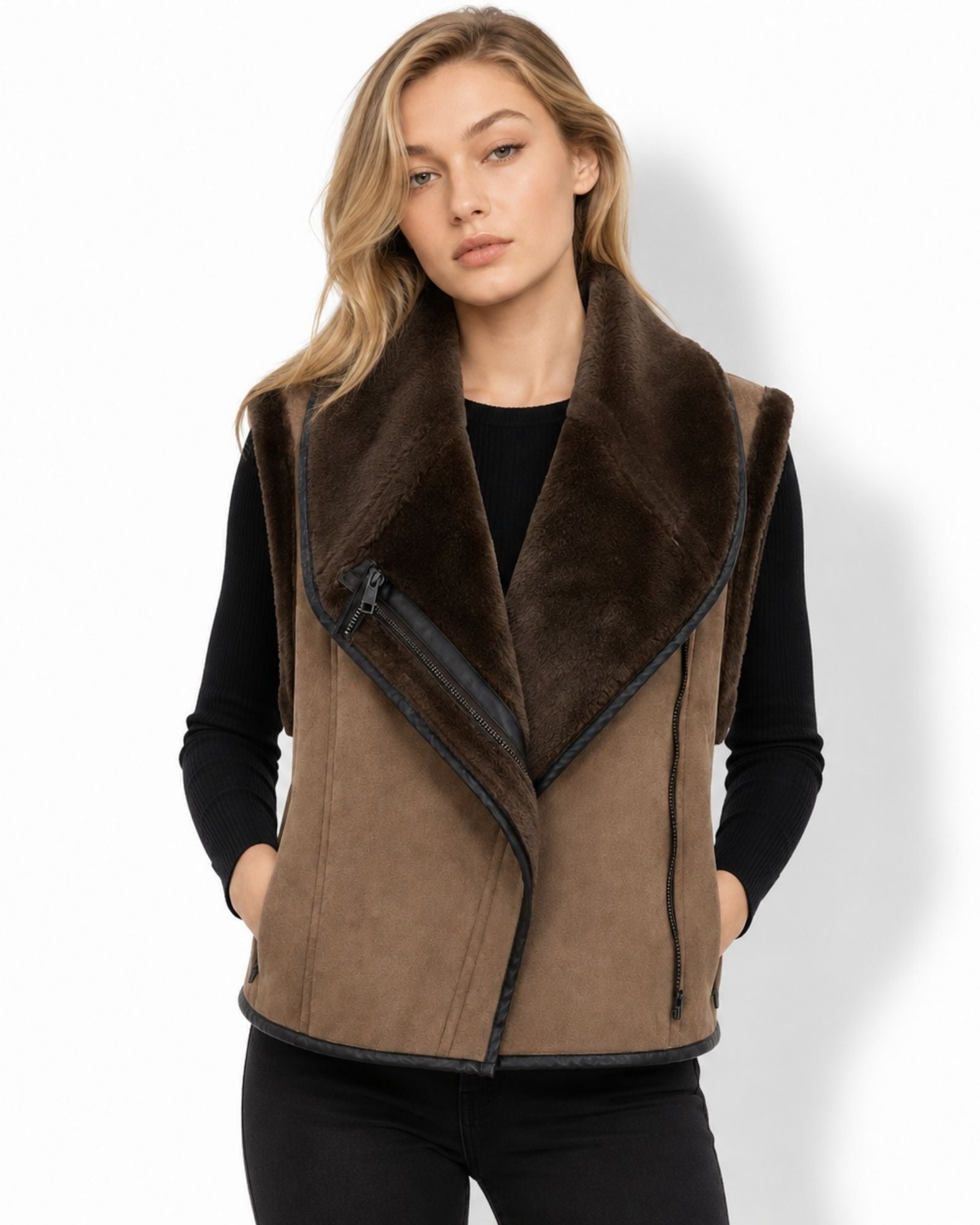 Front view of woman wearing brown faux suede shearling moto vest with asymmetrical zip over a black long sleeve top.