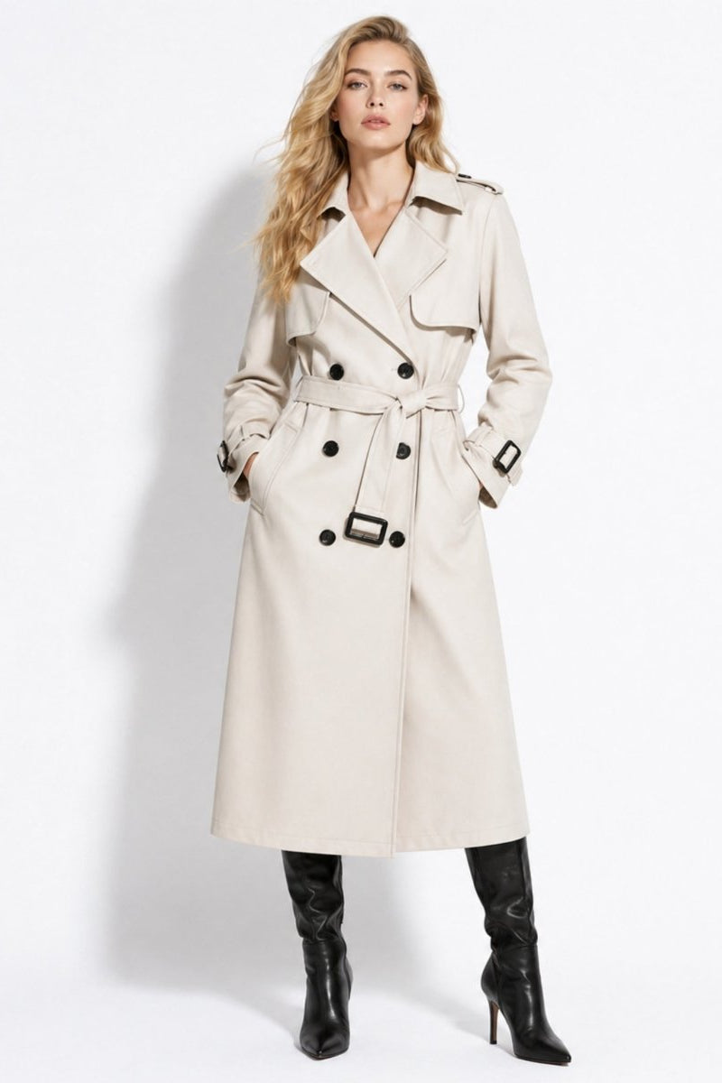 Woman wearing a classic double breasted ivory trench coat with waist belt, dark buttons, and black knee high stiletto boots.