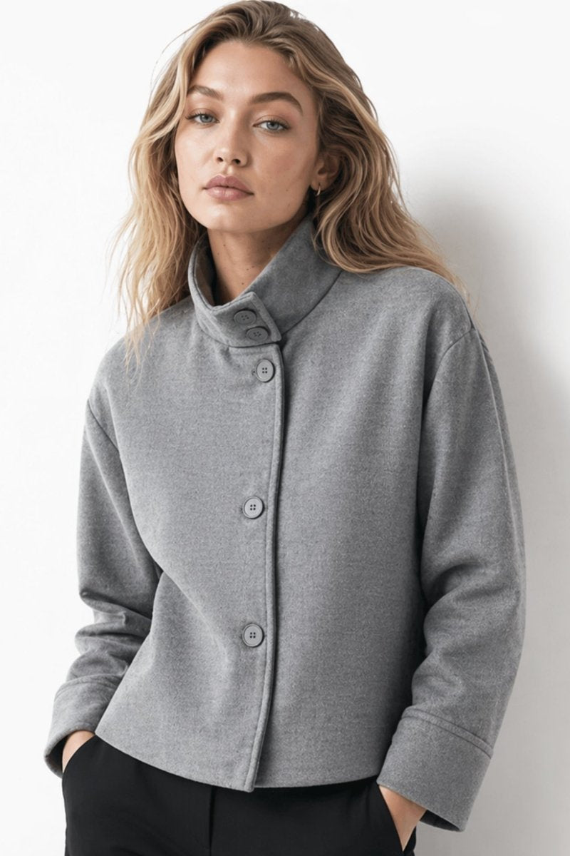 Woman wearing a grey cropped wool blend funnel neck jacket with black trousers, front view, by Fenlo Form.