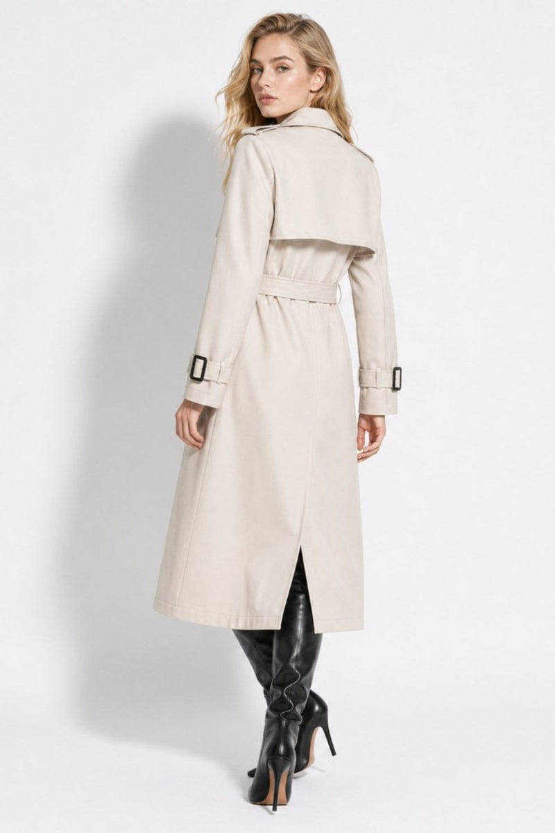 Back view of a women's beige trench coat highlighting the traditional rear storm flap, tied waist belt, and center back vent slit.