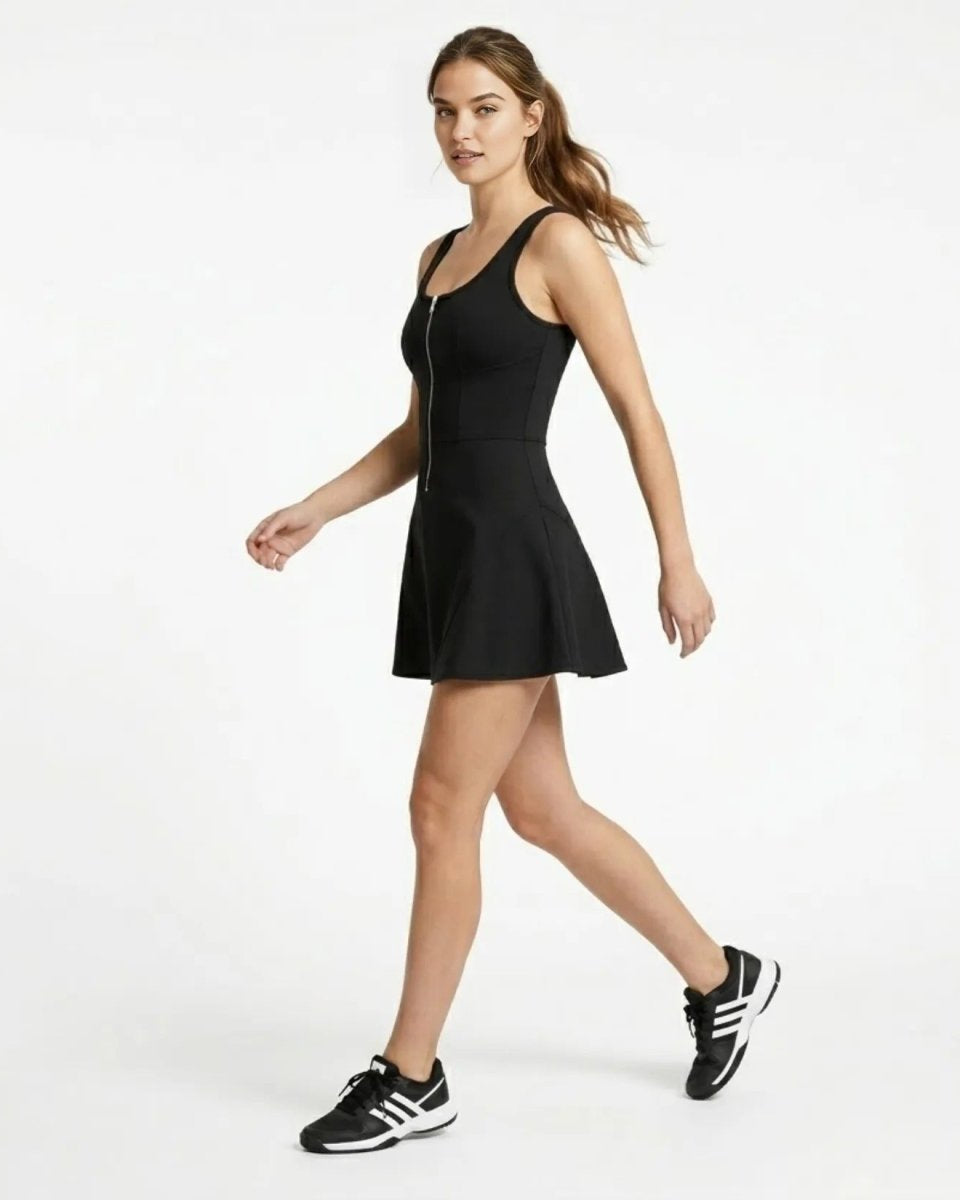 Side profile of woman walking in black sleeveless workout mini dress showing stretch fabric movement