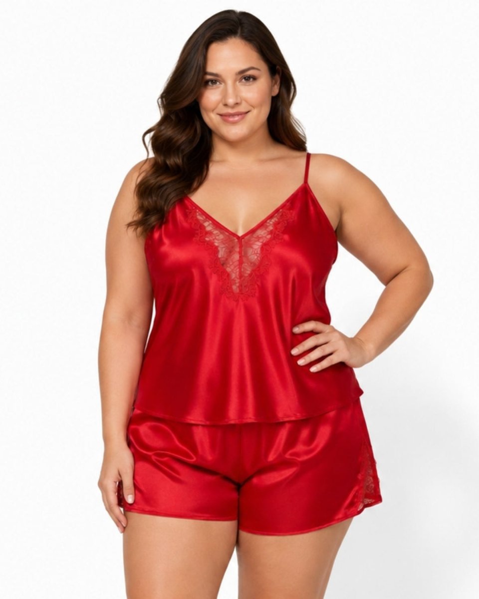 A woman modeling a two-piece red satin lingerie set with a lace-trimmed camisole top and matching shorts against a plain white studio background.