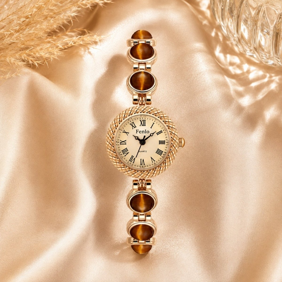 Flat lay lifestyle image of the women's gold jewelry watch with tiger's eye stones resting elegantly on luxurious gold silk fabric.