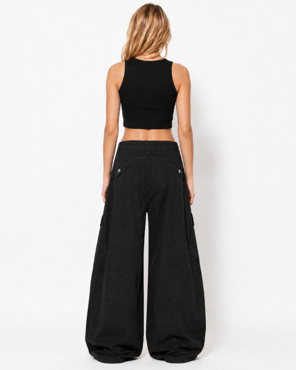 A woman viewed from the back wearing a black sleeveless crop top and very wide-leg black pants against a plain white studio background.
