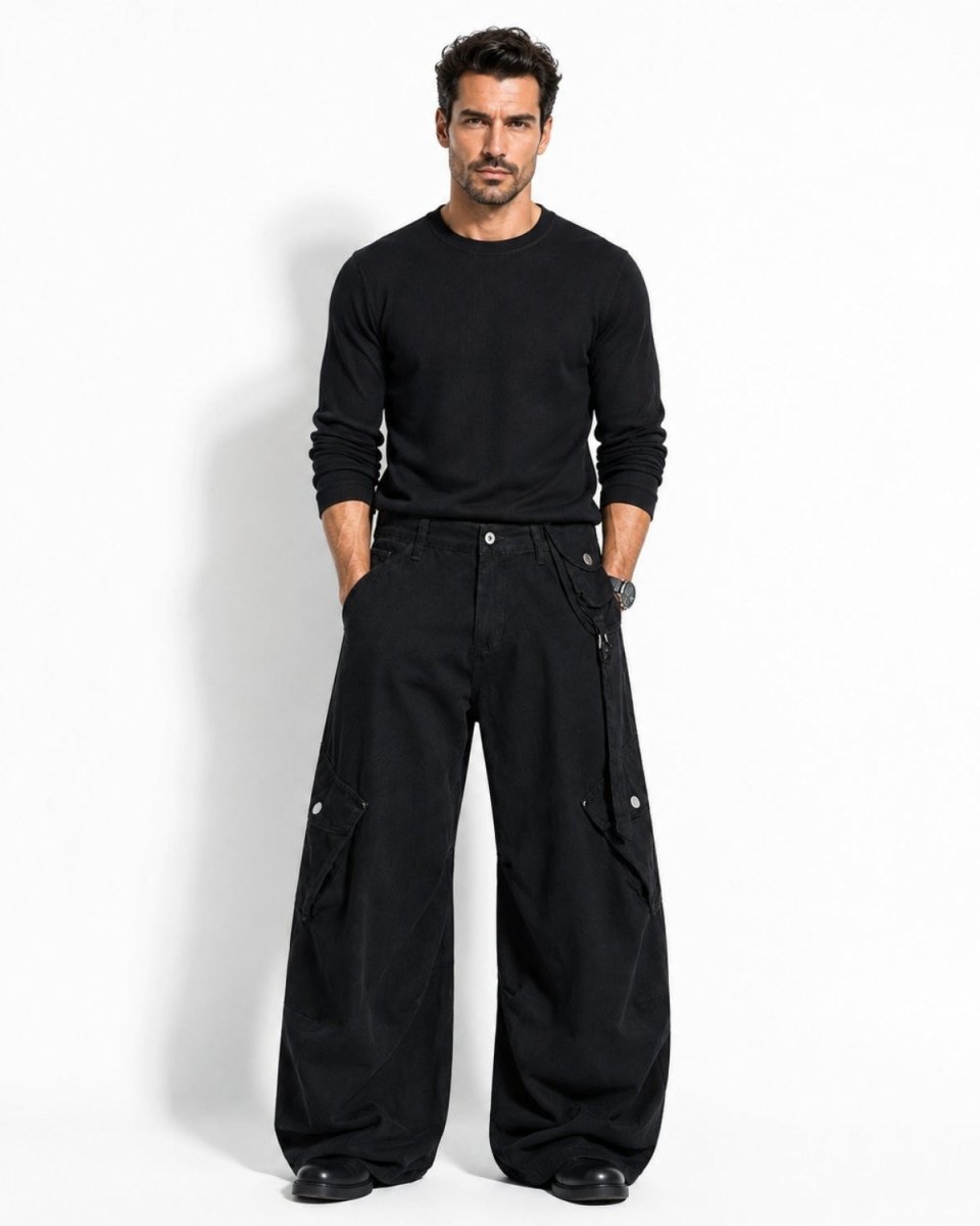 A man modeling a black long-sleeve crewneck shirt and black wide-leg cargo pants with side utility pockets, standing against a plain white studio background.