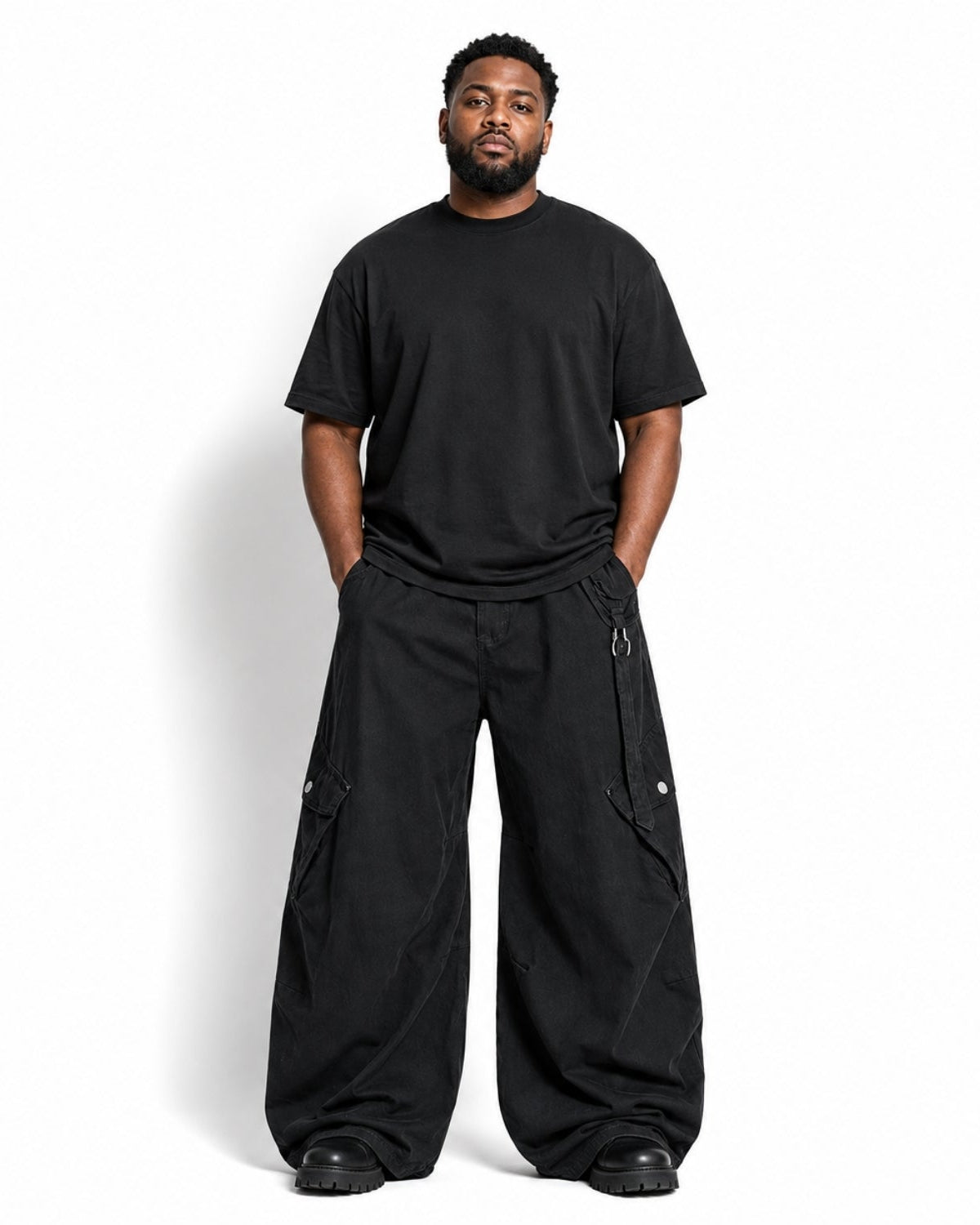 A man modeling a black crewneck t-shirt and matching black wide-leg cargo pants against a plain white studio background.