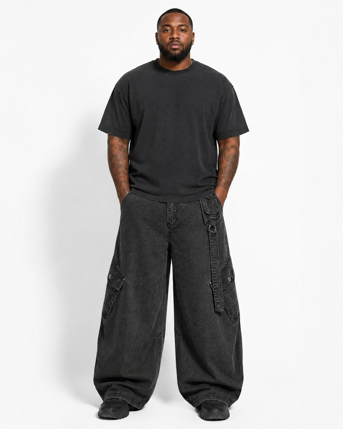 A man modeling a black crewneck t-shirt and wide-leg black cargo pants against a plain white studio background.