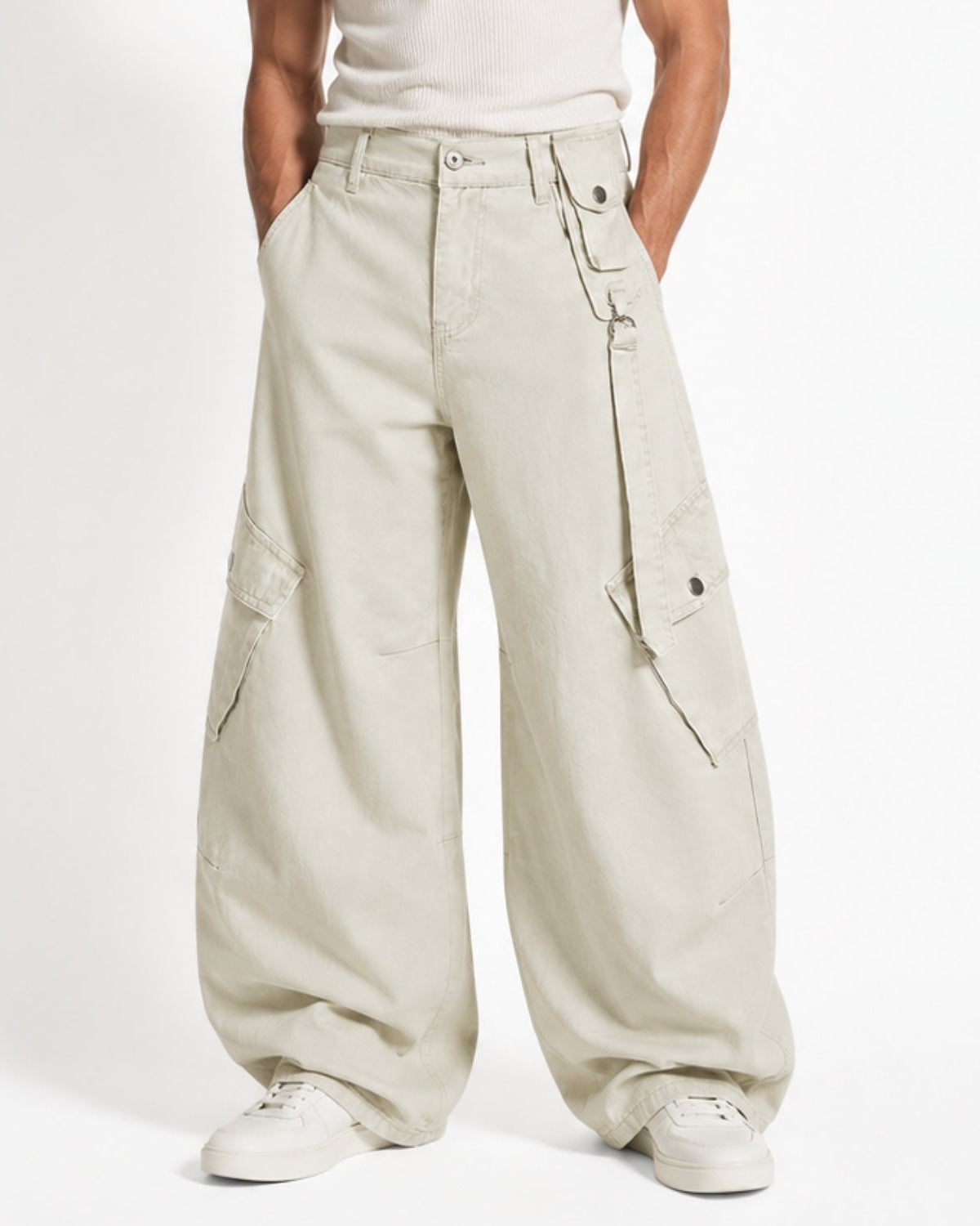 A person wearing oversized light beige cargo pants with multiple flap pockets, shown from the waist down against a plain light background.