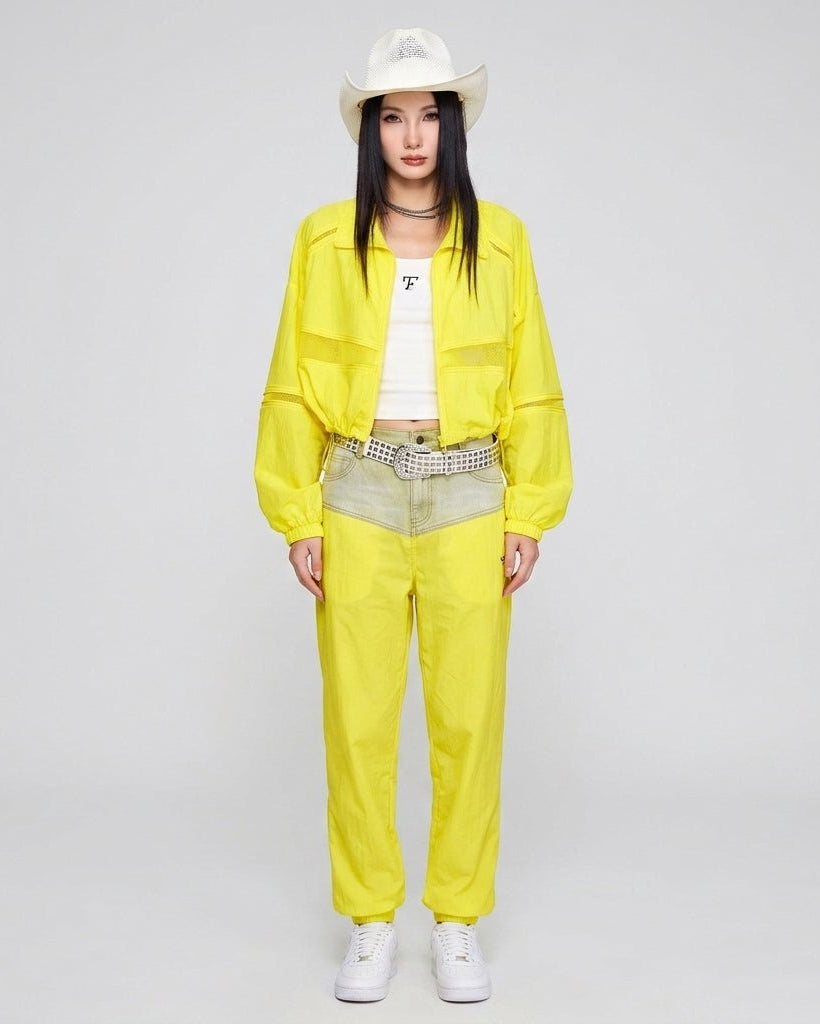 Full body shot of fashion model wearing bright yellow cropped windbreaker jacket paired with matching neon track pants.