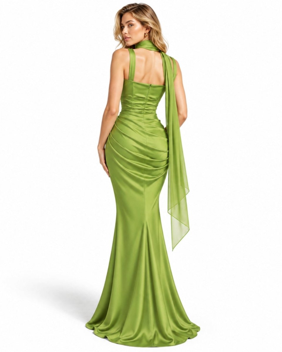 A woman modeling a yellow evening gown from the back, featuring a halter neck, ruched bodice, and a long sheer draped train, set against a plain white background.