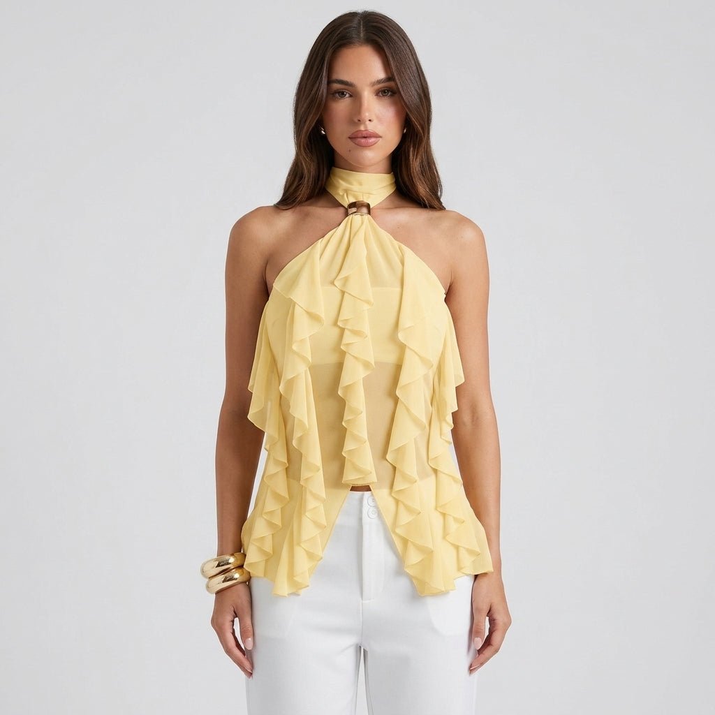 Front view of woman wearing Kouvr pale yellow sheer chiffon ruffle halter top with gold neck hardware and white trousers.