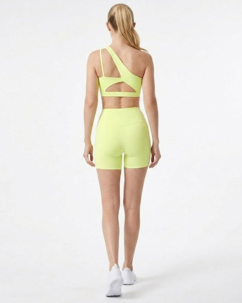 Back view of yellow activewear set showcasing strappy back cutout details on sports bra and fitted biker shorts