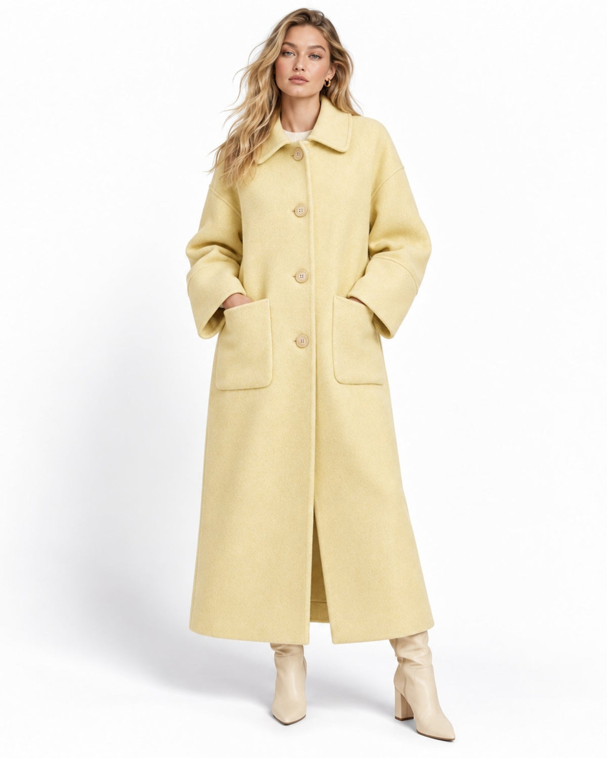 A woman modeling a long, light yellow wool-blend coat with large front pockets and button closure, paired with beige ankle boots, against a plain white studio background.