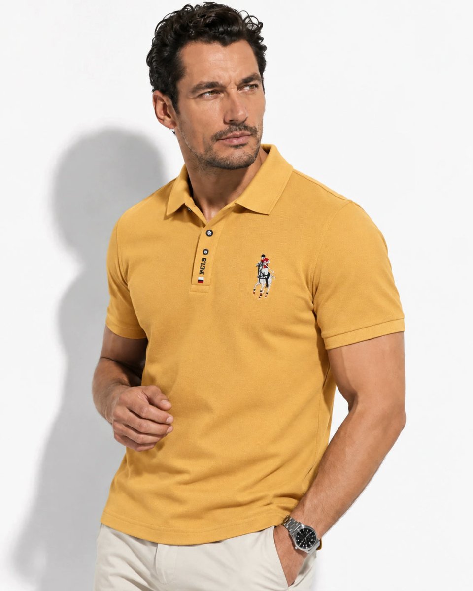 Brix: Model im gelben Poloshirt mit Brustmotiv und kurzer Knopfleiste vor hellem Hintergrund.