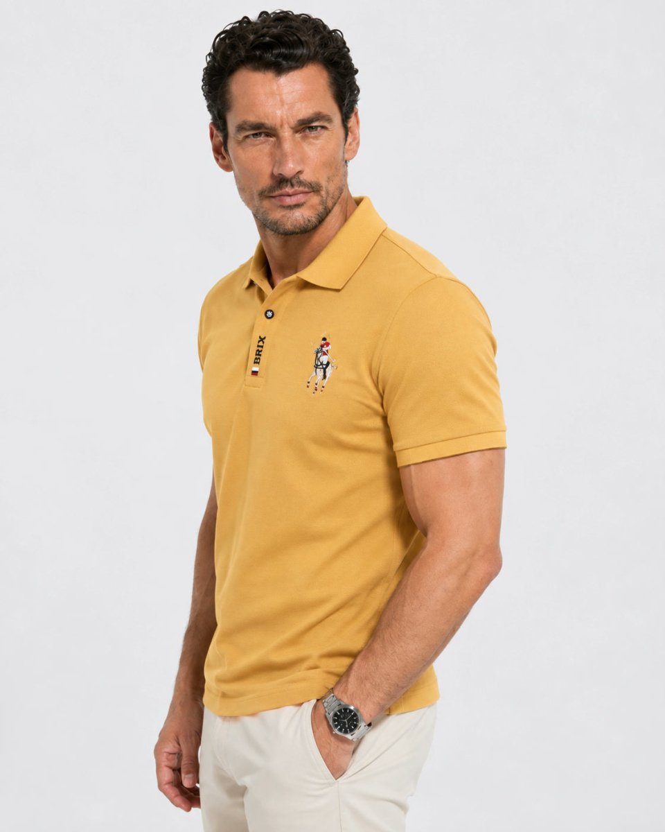 Brix: Seitliche Vorderansicht des gelben Poloshirts mit Brustmotiv am Model.