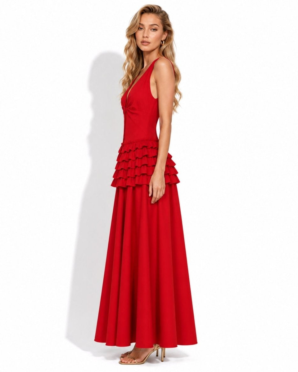 A woman modeling a sleeveless red maxi dress with a tiered ruffle waist, photographed against a plain white studio background.