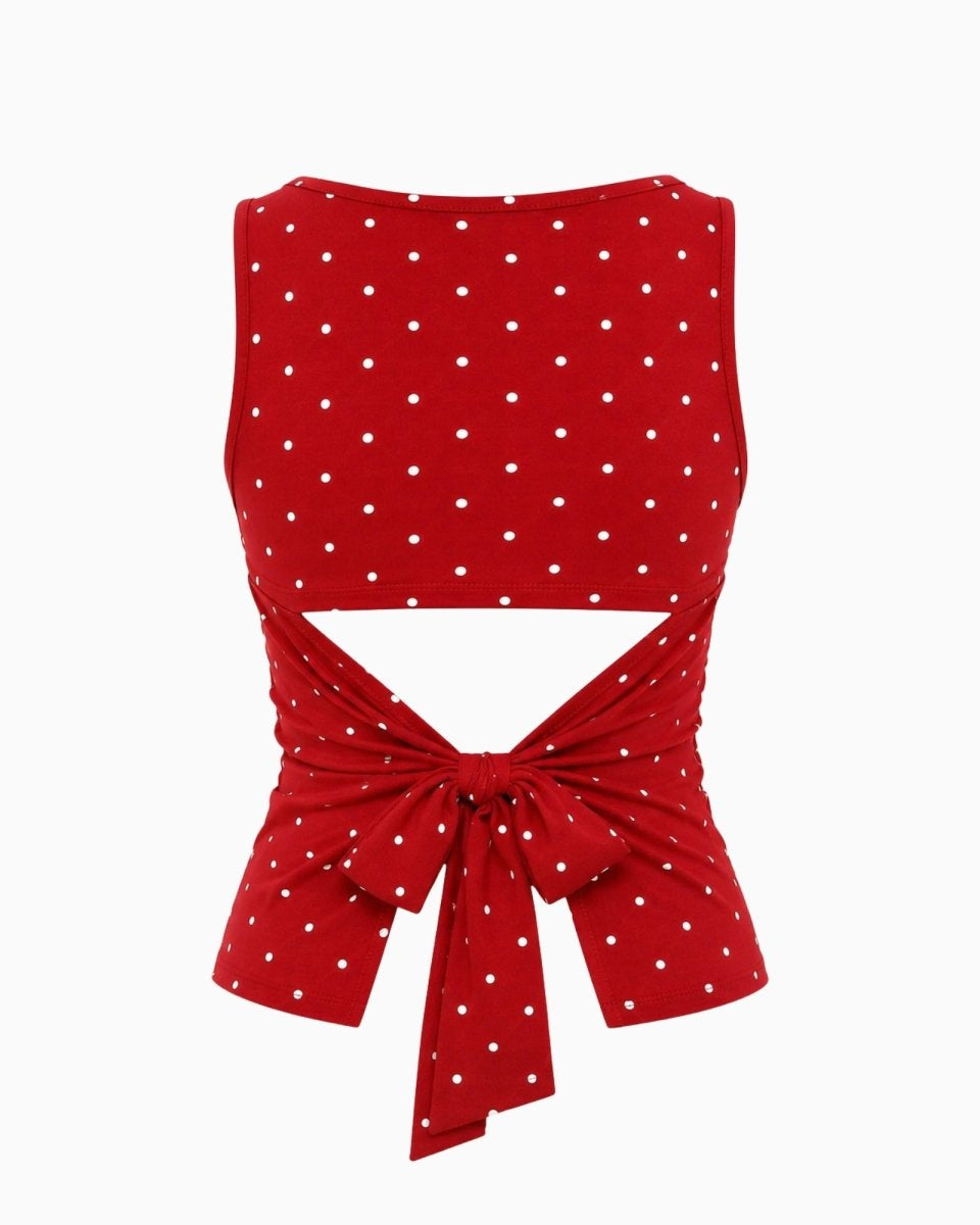 Red sleeveless crop top with white polka dots and a tie-front waist cutout, shown on a plain light gray background.