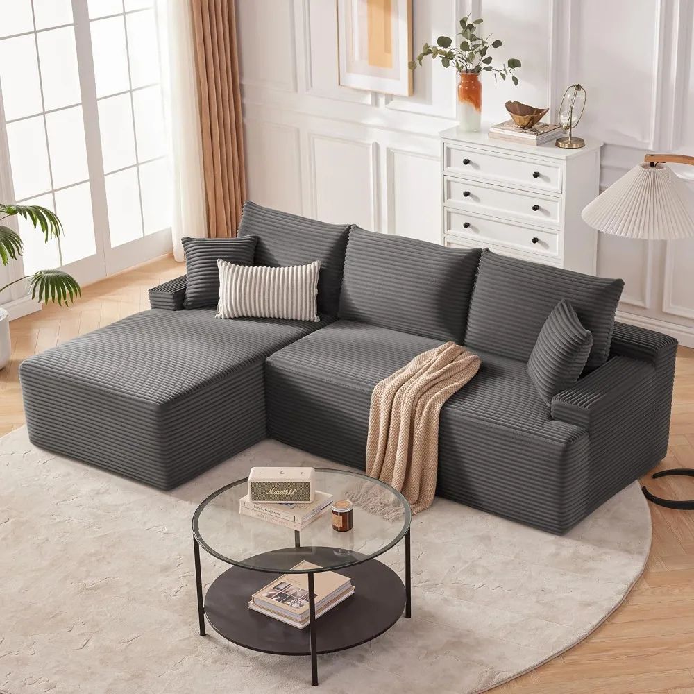 Kouvr modular deep seat sofa in black and dark grey corduroy shown in an L-shape with a beige throw blanket