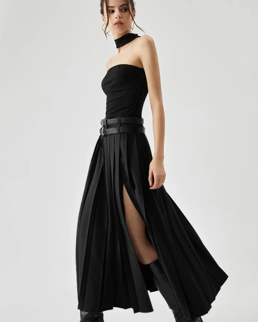 Woman wearing a black strapless dress with a high slit on a white background