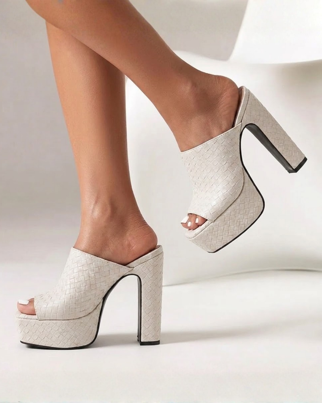 A pair of off-white woven platform mule heels with block heels, shown on a model's feet against a clean white studio background.