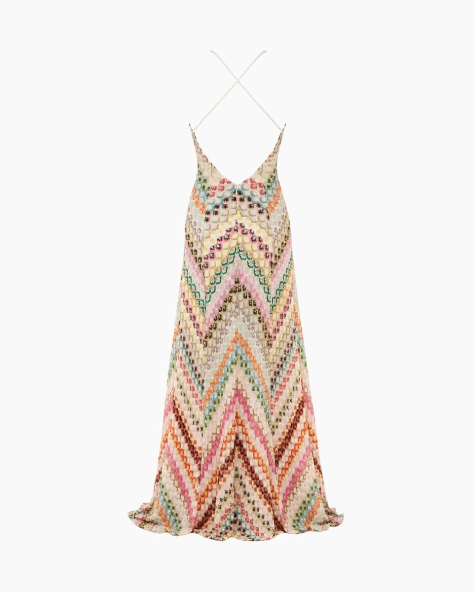 A sleeveless crochet knit maxi dress with thin spaghetti straps, featuring a colorful chevron pattern in pink, green, orange, and brown on a cream base, shown hanging against a plain white background.
