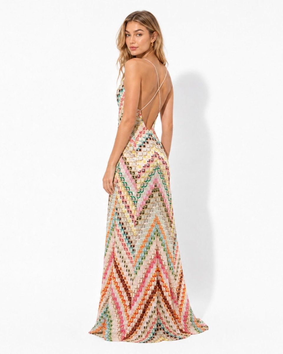 A woman modeling a long, sleeveless maxi dress with a colorful chevron knit pattern, shown from the back against a plain white studio background.