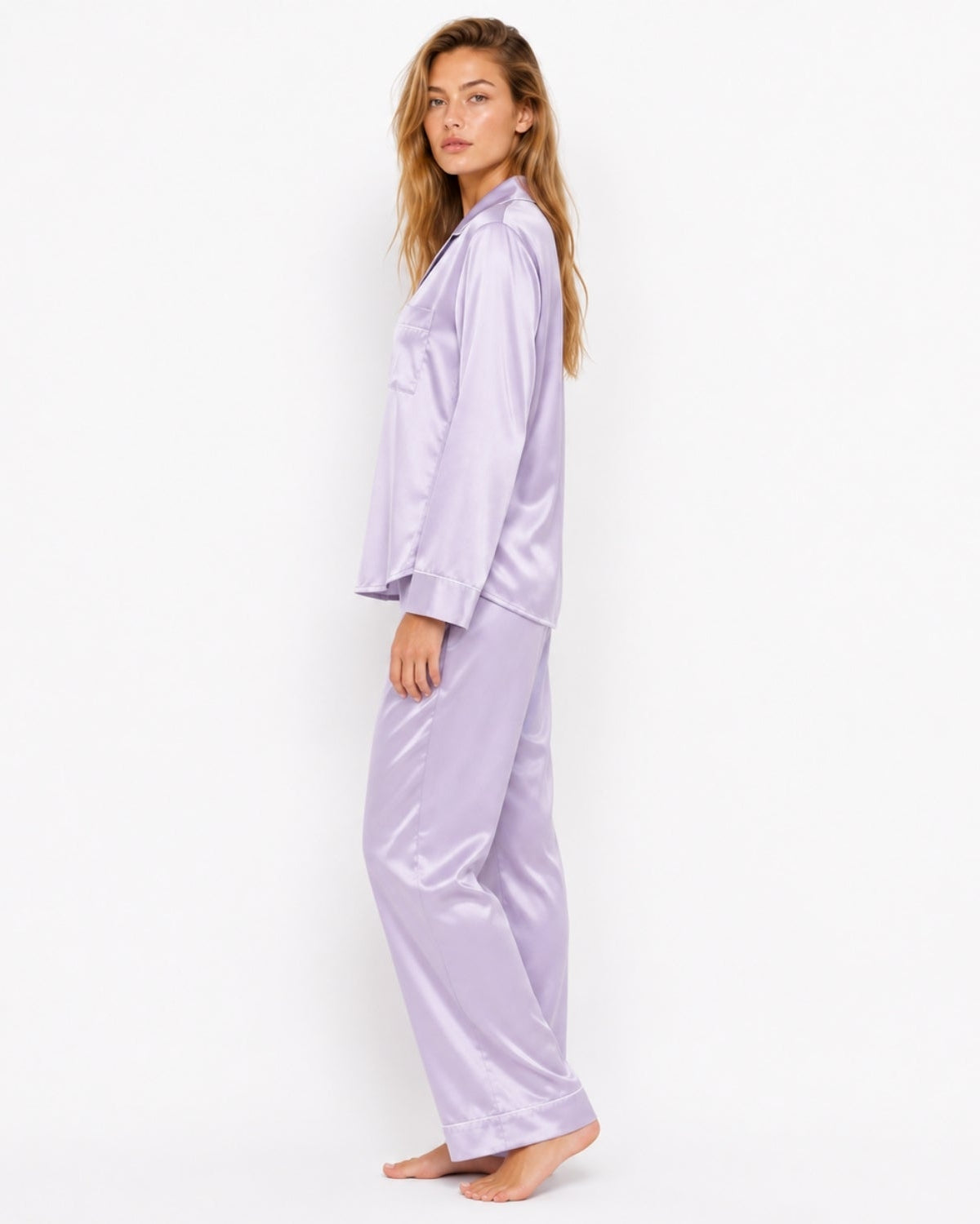 A woman modeling a two-piece lavender satin pajama set, featuring a long-sleeve button-up top and matching wide-leg pants, set against a plain white studio background.