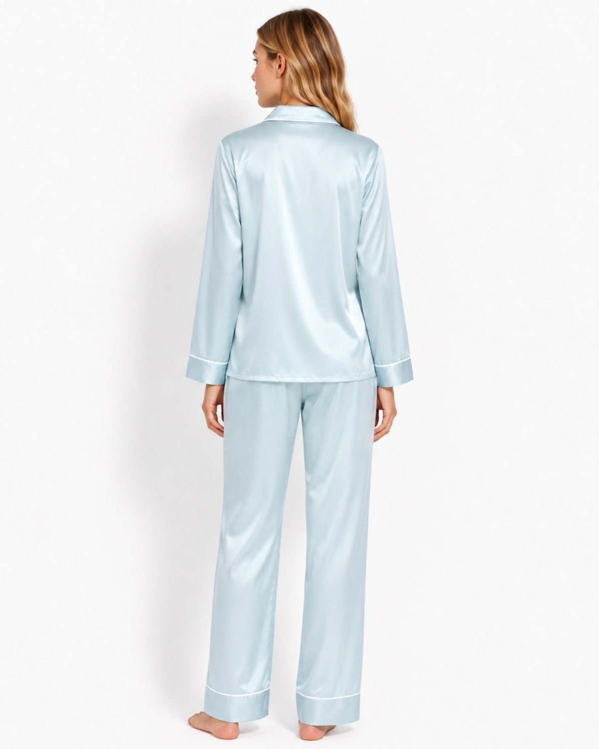 A woman wearing a light blue satin pajama set, shown from the back against a plain white studio background.