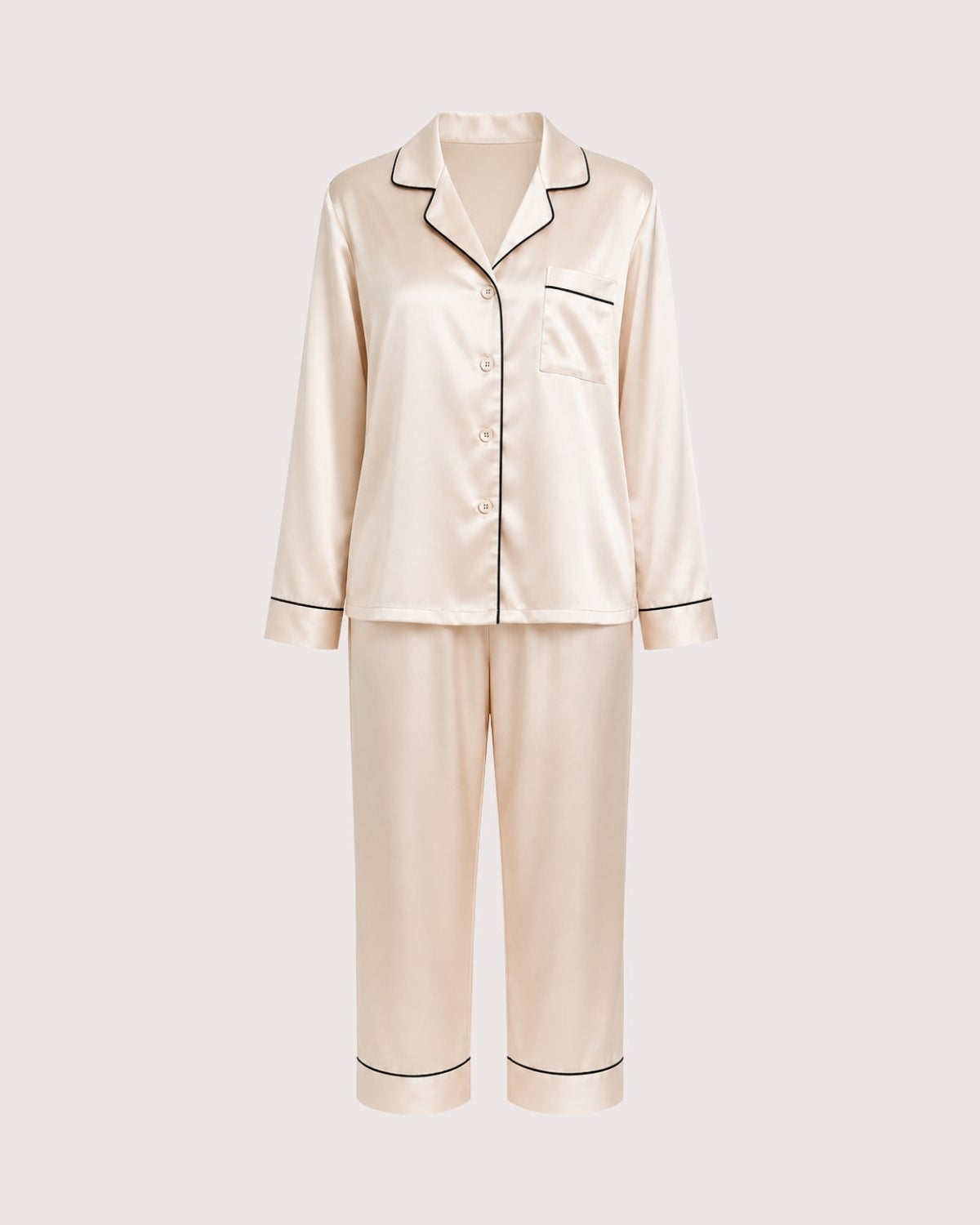 A two-piece satin pajama set in a light champagne beige color, featuring a long-sleeve button-up top with black piping and matching wide-leg pants, shown against a solid light gray background.