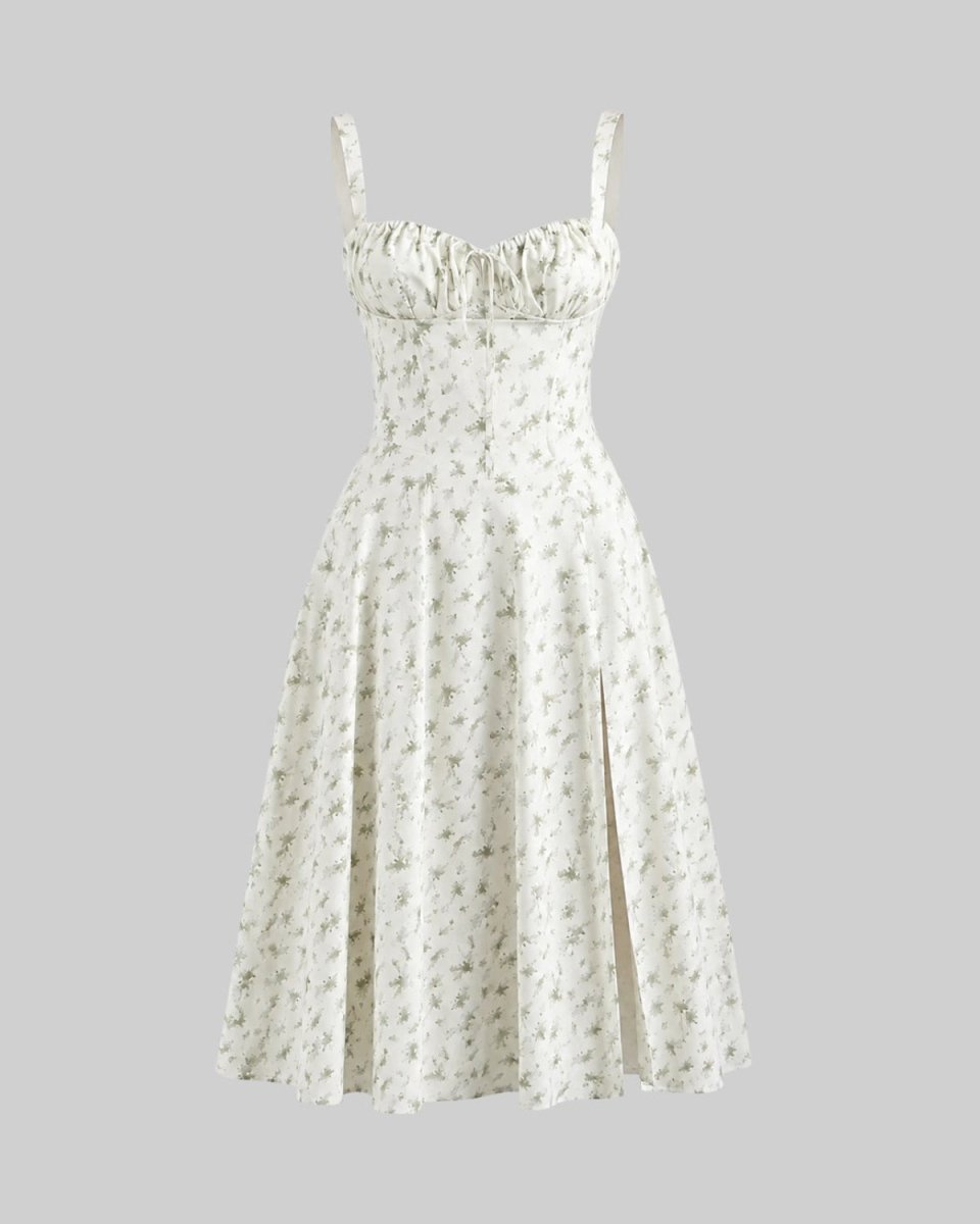 A sleeveless white midi dress with a delicate green floral print, featuring a ruffled sweetheart neckline, thin shoulder straps, and a flared skirt with a front slit, shown against a solid gray background.