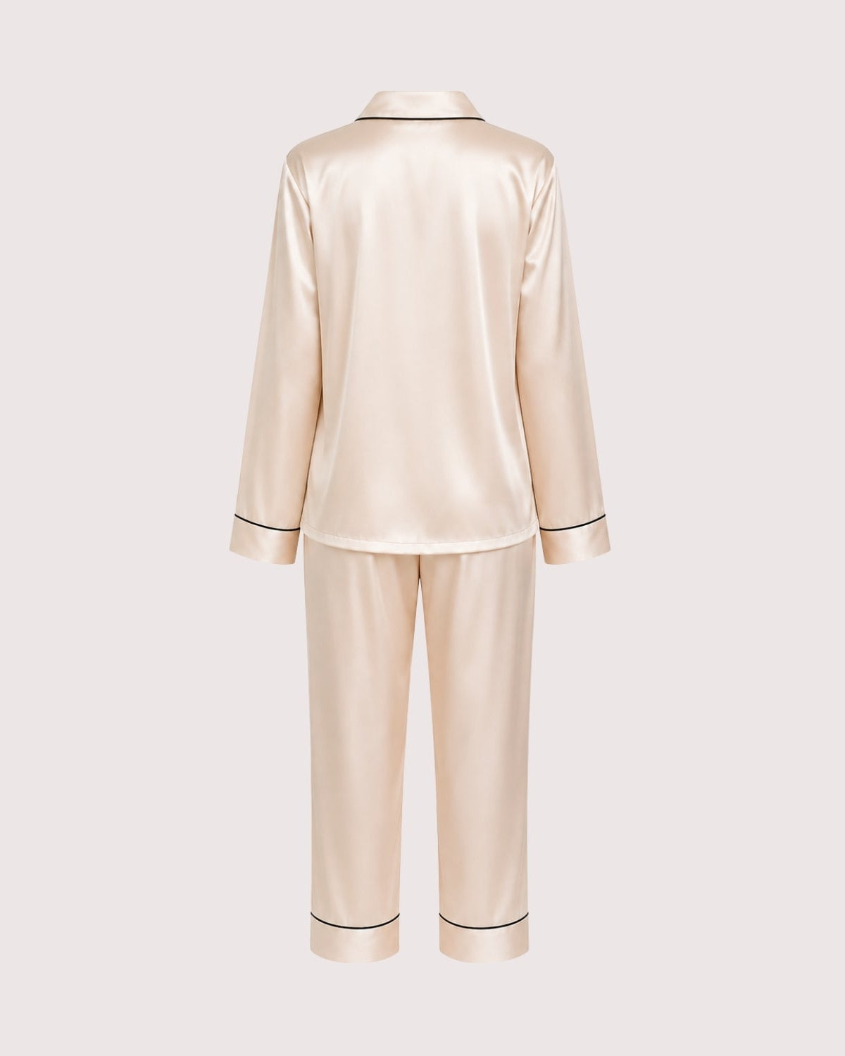 A two-piece satin pajama set in a light champagne beige color, shown from the back. The set includes a long-sleeve top with thin black piping along the collar, cuffs, and hem, and matching straight-leg pants with black piping at the cuffs.