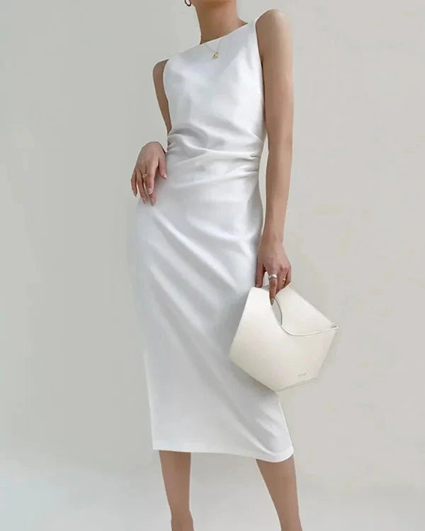 Woman wearing a white one-shoulder dress holding a matching clutch against a plain background
