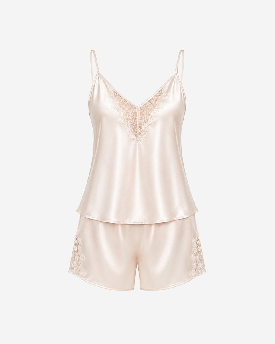 A two-piece satin pajama set in a pale champagne pink color, featuring a camisole top with lace detailing on the chest and matching lace-trimmed shorts, displayed against a solid off-white background.