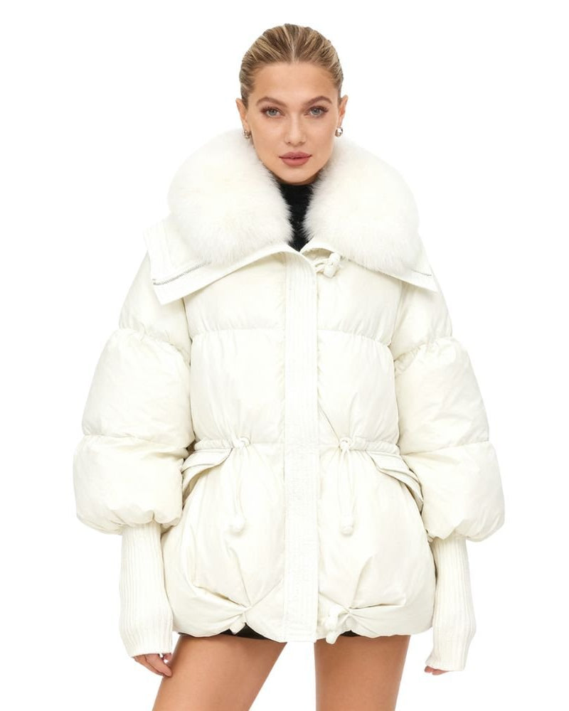 Woman wearing a white kouvr puffer coat with a fur-lined hood on a white background