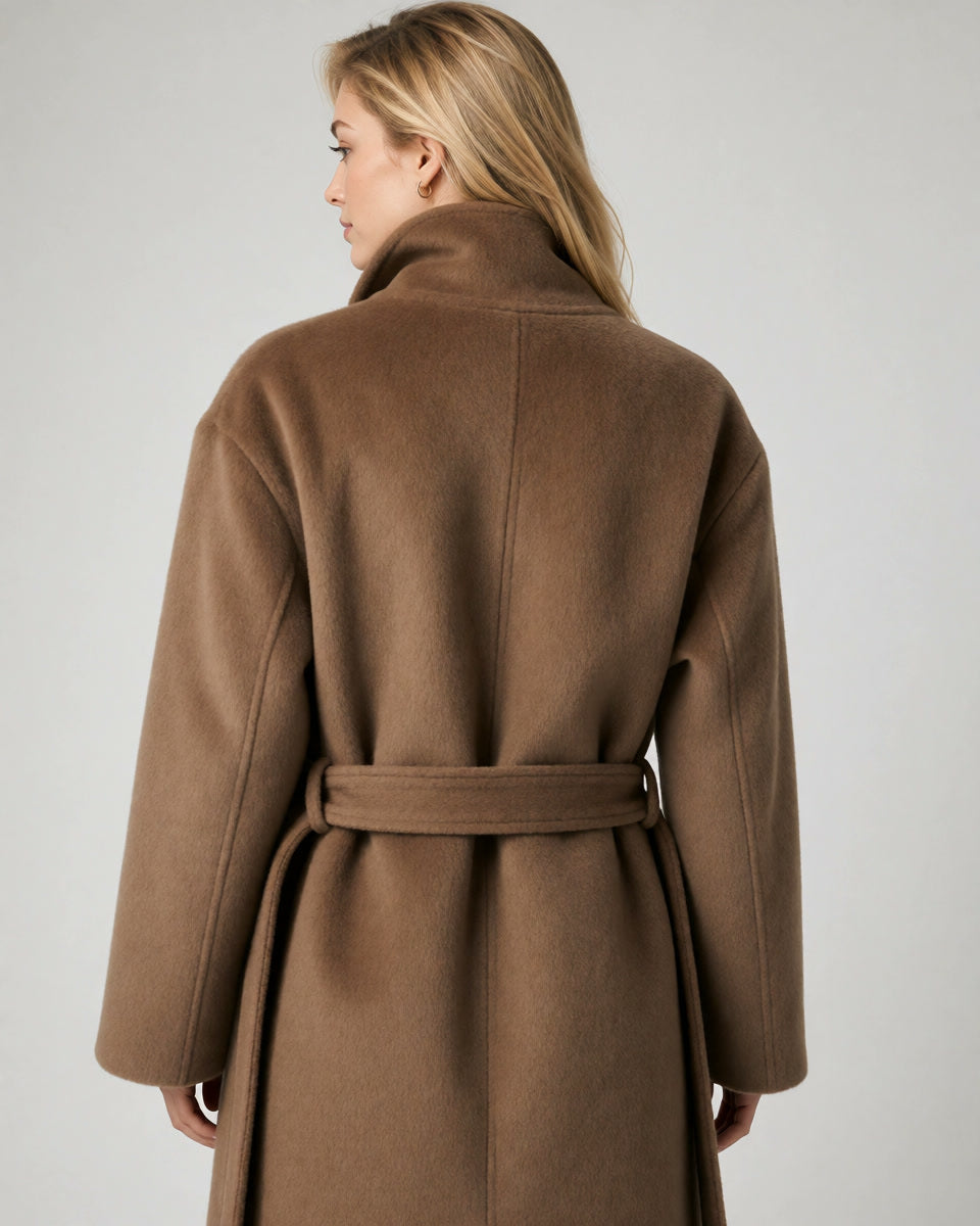 A woman shown from the back wearing a brown wool coat with a matching waist belt, photographed against a plain light gray studio background.